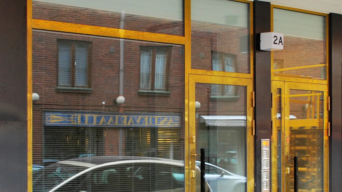 Messinkiverhoillut ovet ja ikkunat liikehuoneiston katujulkisivussa Eirassa