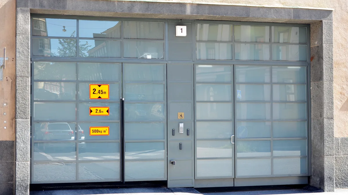 Autohallin konekäyttöiset teräslasiovet rakennuksen sisäänajoaukossa