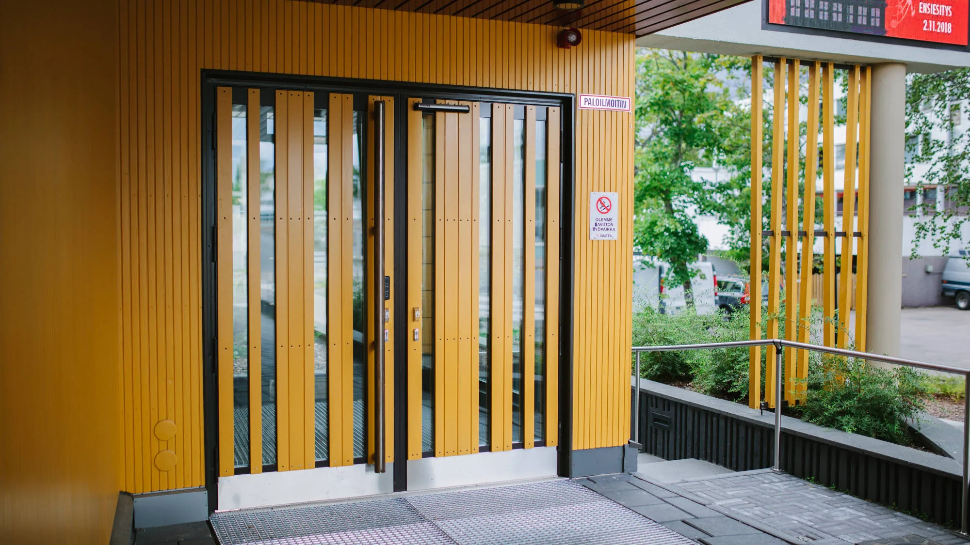 Teatteri Imatran sisäänkäynti, jossa keltaiset teräslasiovet ja puusäleverhoiltu julkisivu